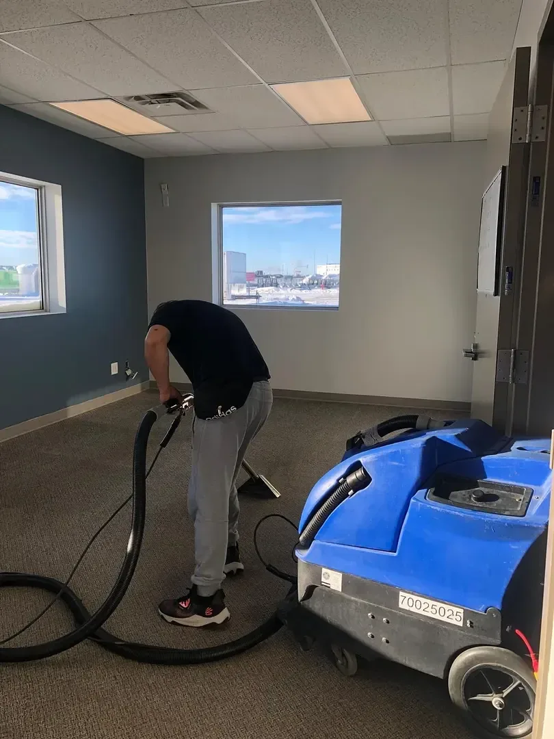 GoFlow technician cleaning carpet with an extraction machine in a room