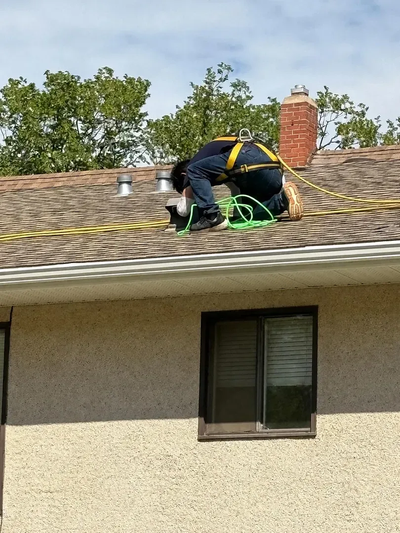 GoFlow technician with vent-cleaning equipment on a roof